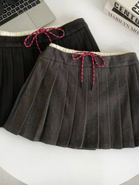 Gray pleated skirt with pink drawstring on a white surface