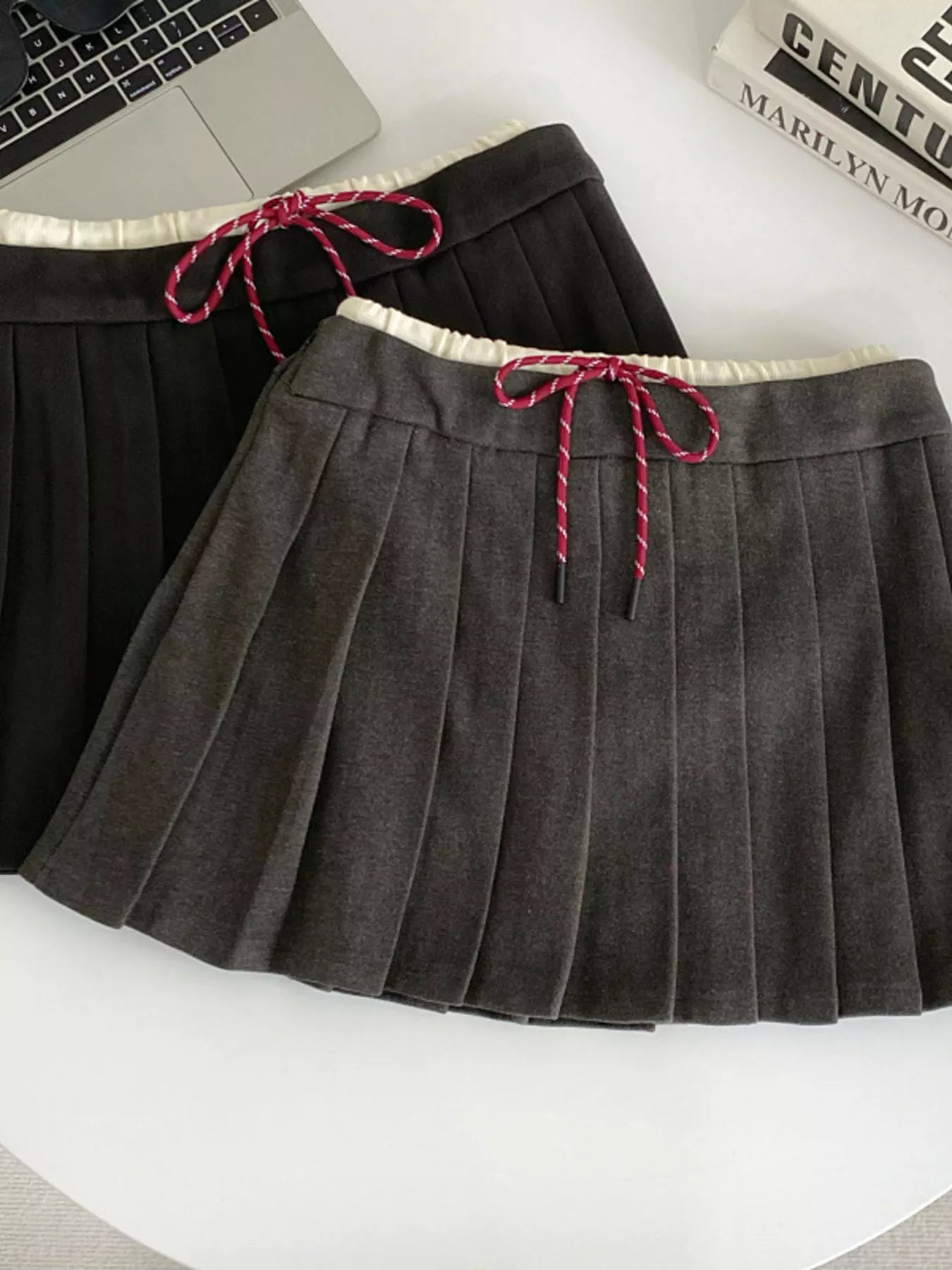 Gray pleated skirt with pink drawstring on a white surface