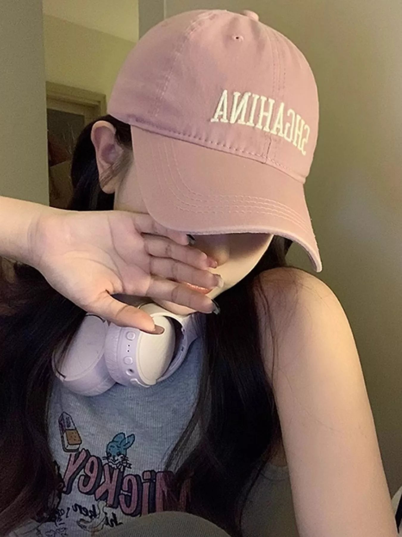 Person wearing a pink cap with 'SHEHANNA' text, covering their face.