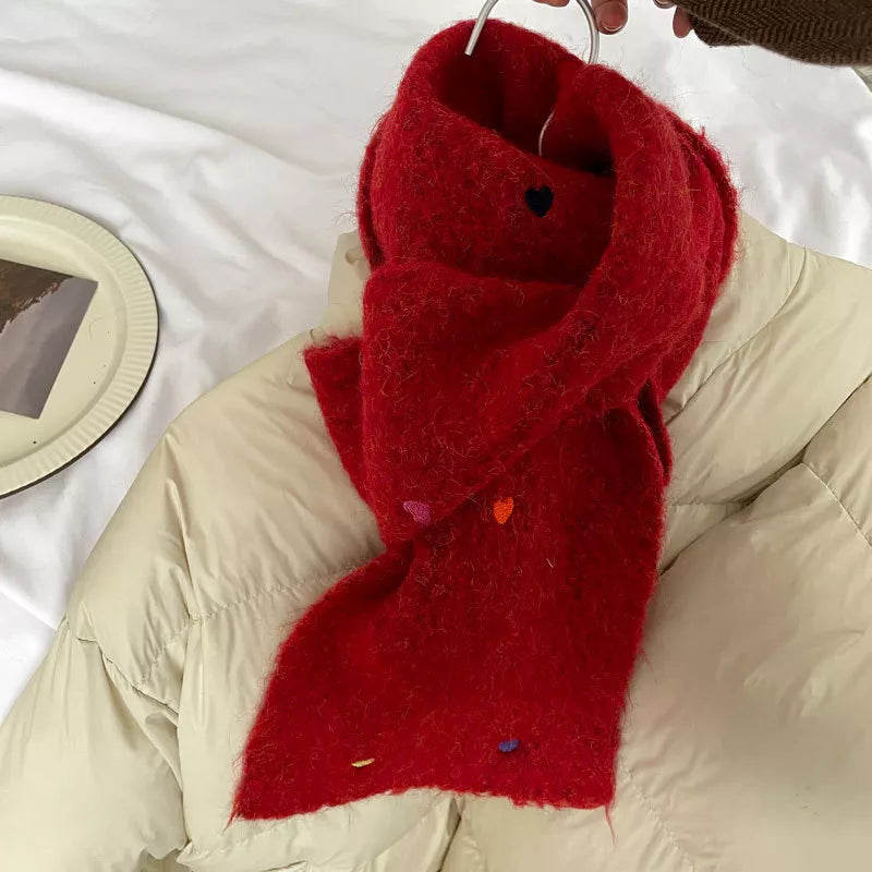 Red scarf draped over a beige puffer jacket on a white surface