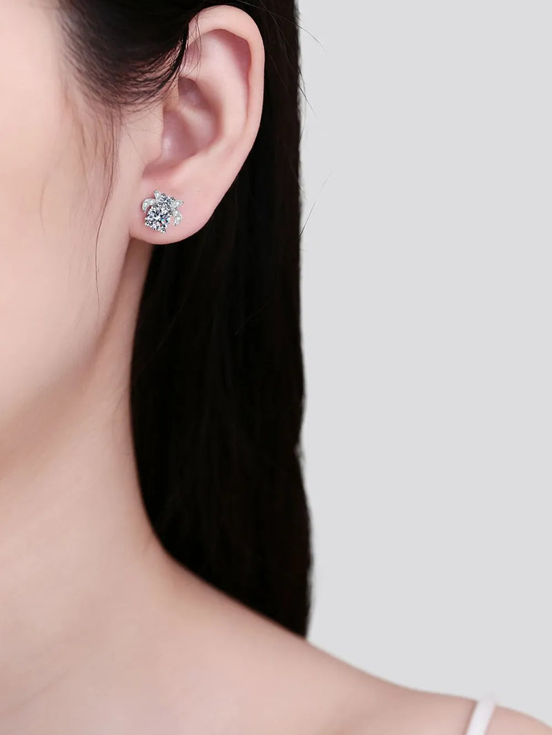 Close-up of a person wearing diamond stud earrings with a plain background