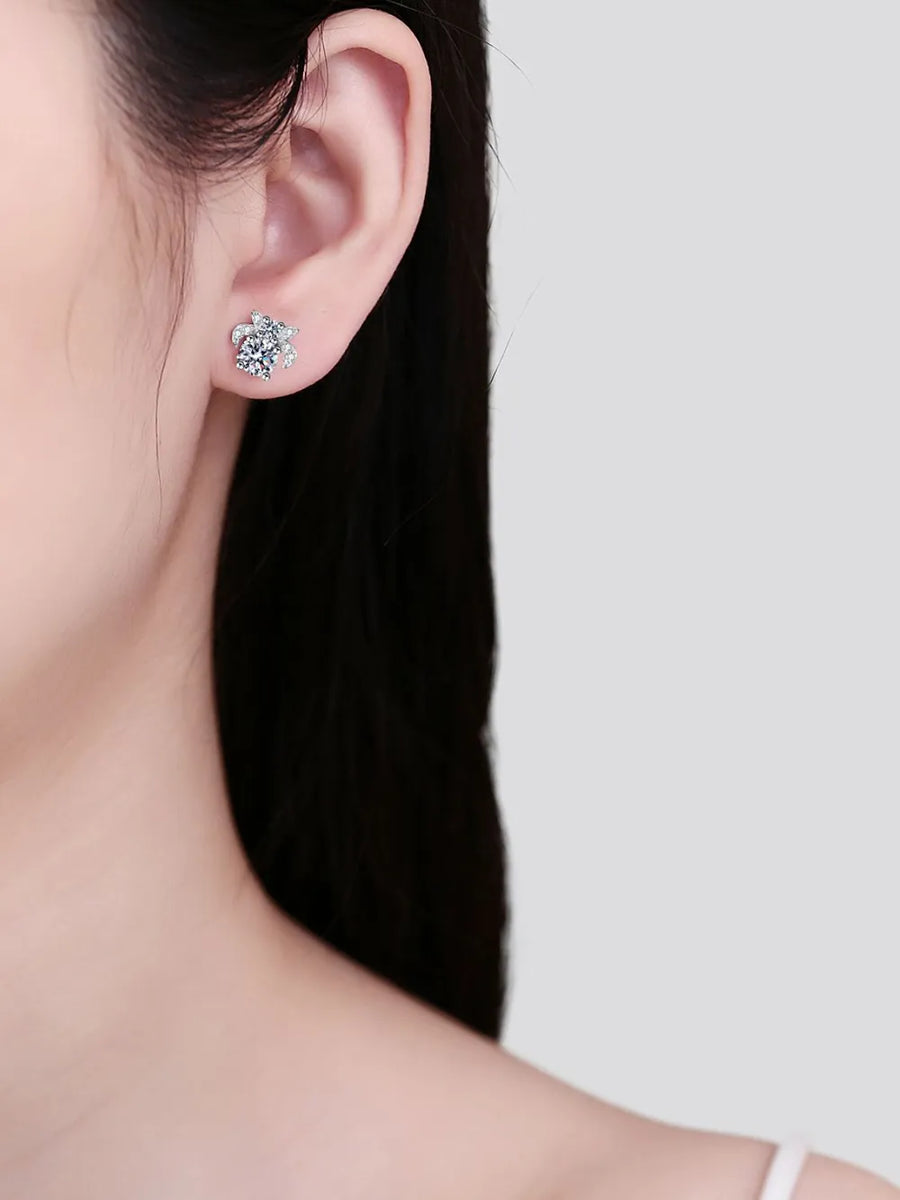 Close-up of a person wearing diamond stud earrings with a plain background