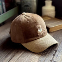 Brown cap with teddy bear emblem on a wooden surface