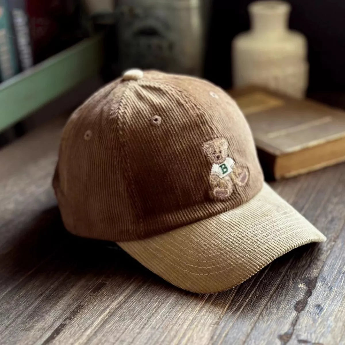 Brown cap with teddy bear emblem on a wooden surface