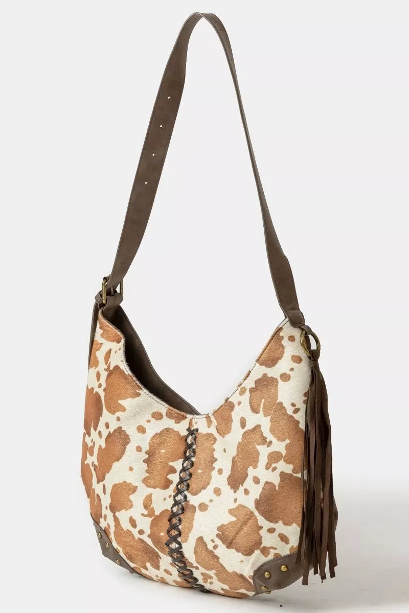 Leopard print handbag with brown leather strap on a white background
