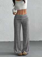 Person wearing black and white striped pants against a plain background