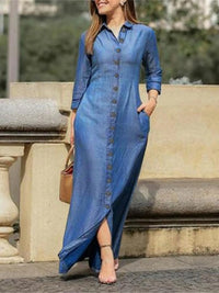 Woman wearing a long blue denim dress standing outdoors.