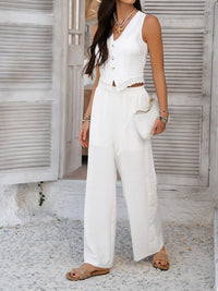 Woman wearing a white outfit with wide-leg pants in front of a white door.
