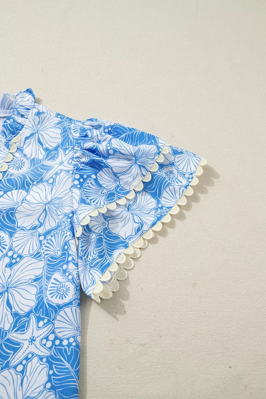 Blue floral patterned fabric with white trim on a beige background