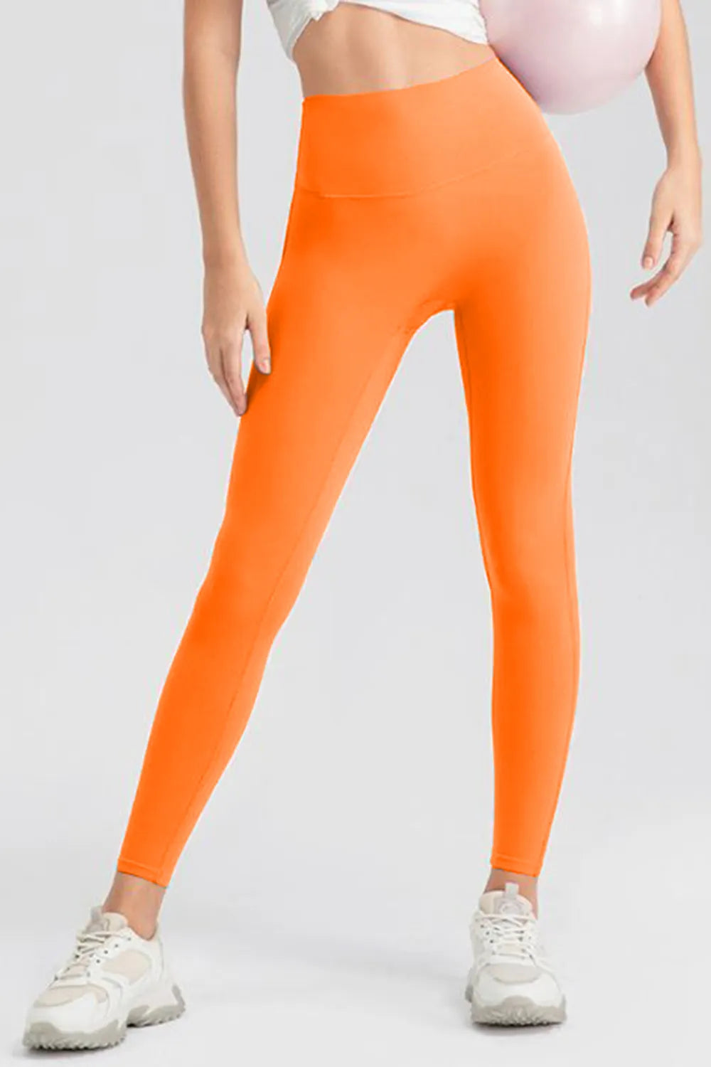 Person wearing bright orange leggings on a light gray background