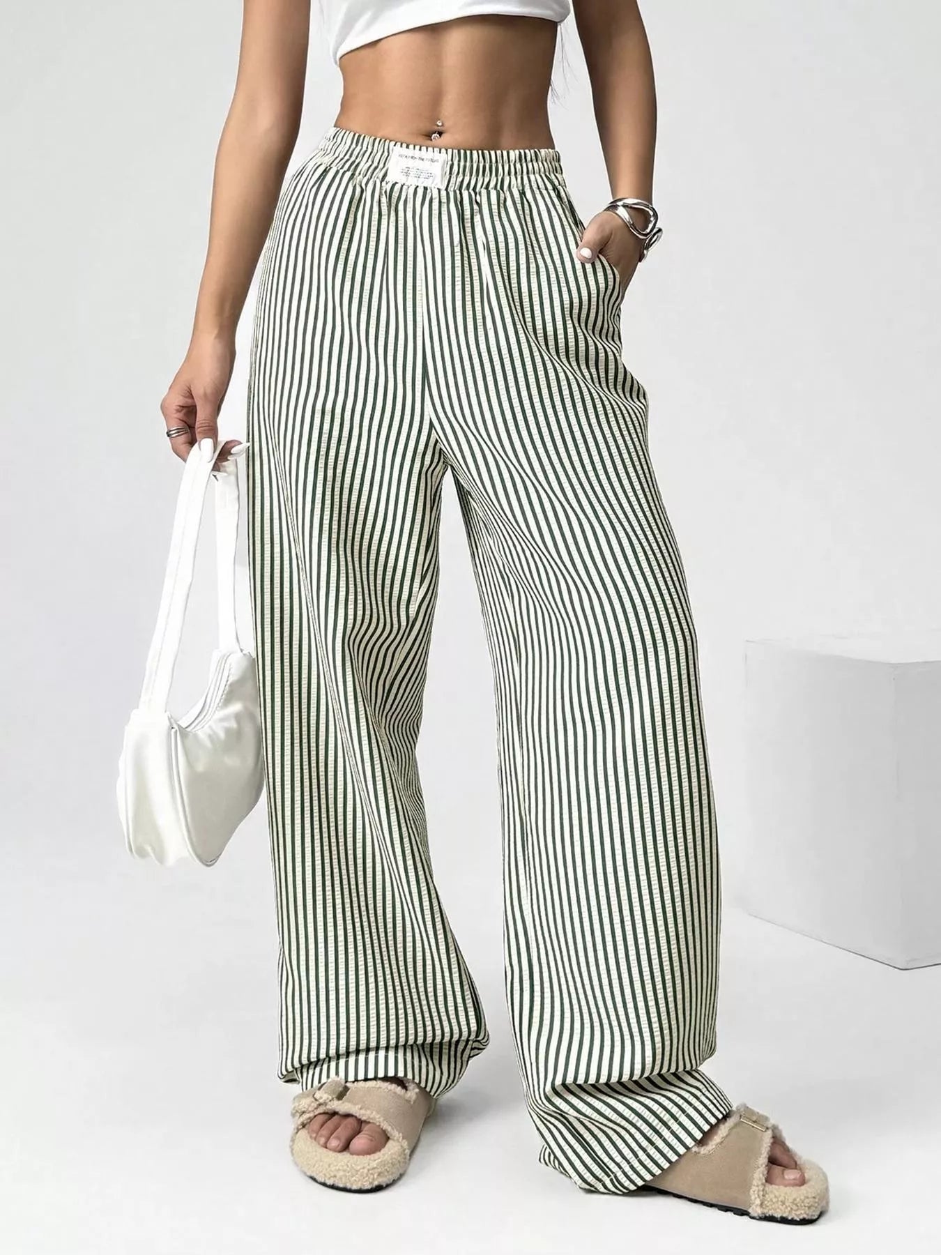 Person wearing green and white striped pants on a plain background