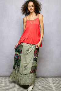 Woman wearing a red top and patterned pants against a gray background