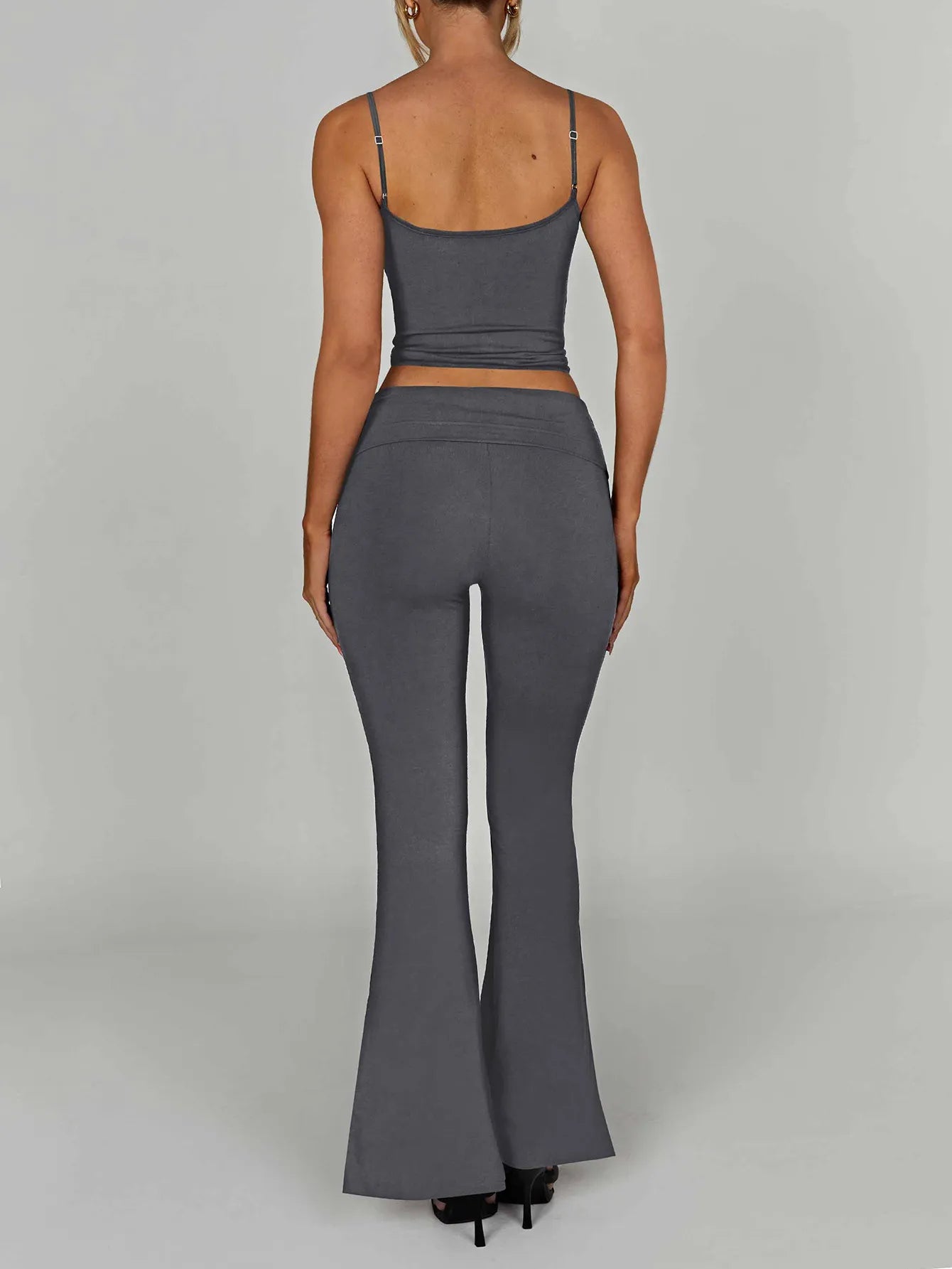 Person wearing a gray crop top and flared pants on a plain background