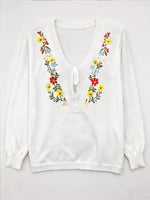 White blouse with colorful floral embroidery on a white background
