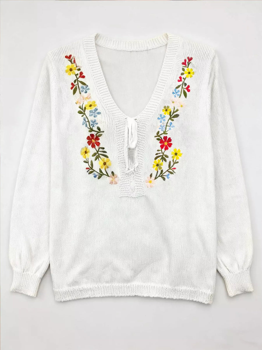 White blouse with colorful floral embroidery on a white background