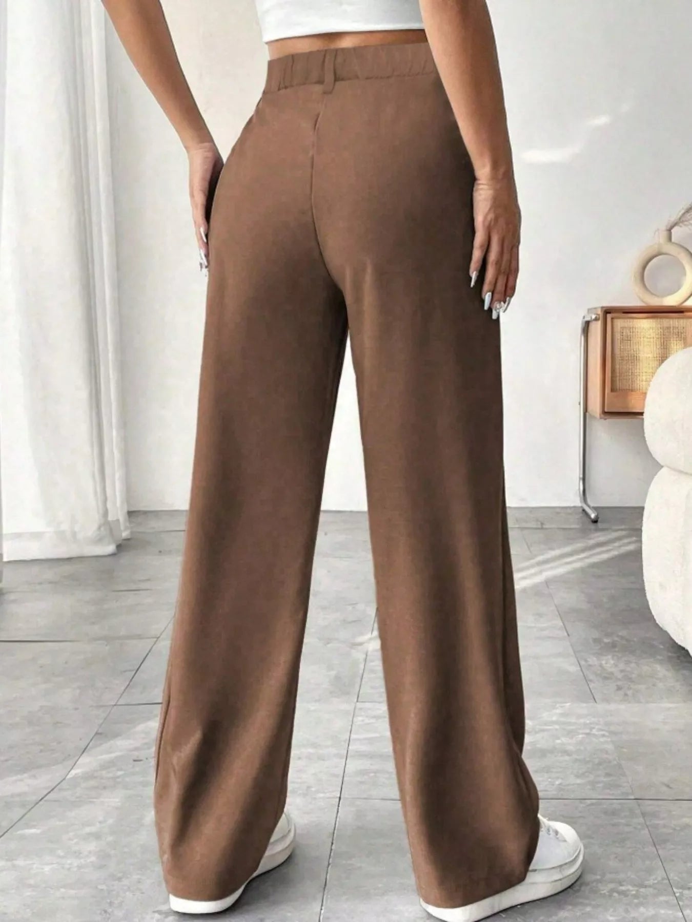 Brown wide-leg pants worn by a person in a minimal indoor setting