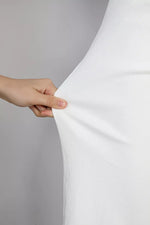 Hand holding a white fabric against a gray background