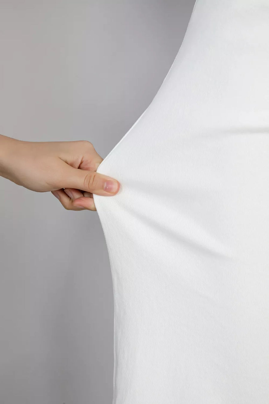 Hand holding a white fabric against a gray background