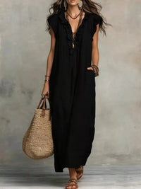 Woman wearing a black sleeveless dress holding a straw bag against a neutral background