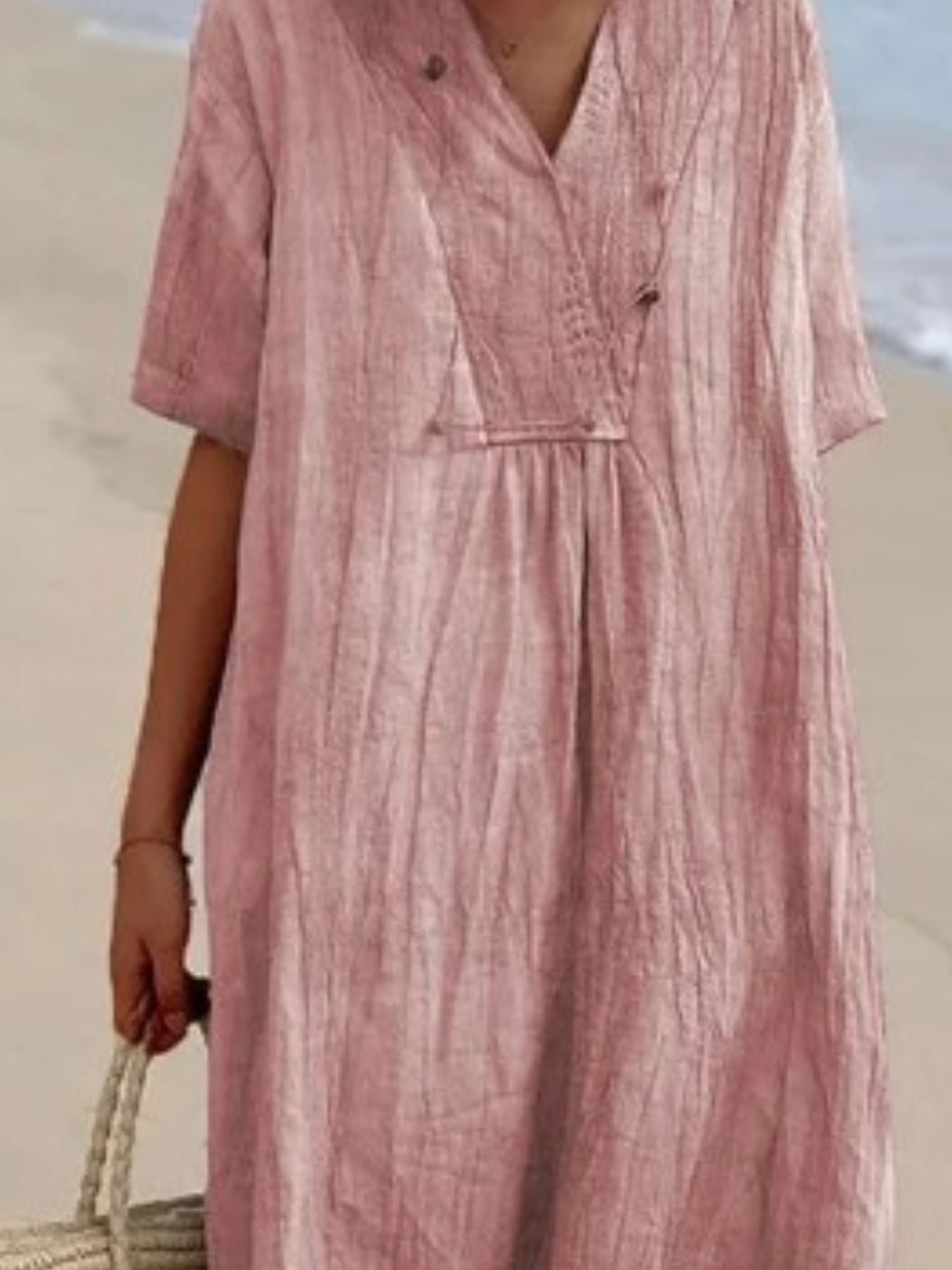Person wearing a pink dress with a blurred beach background