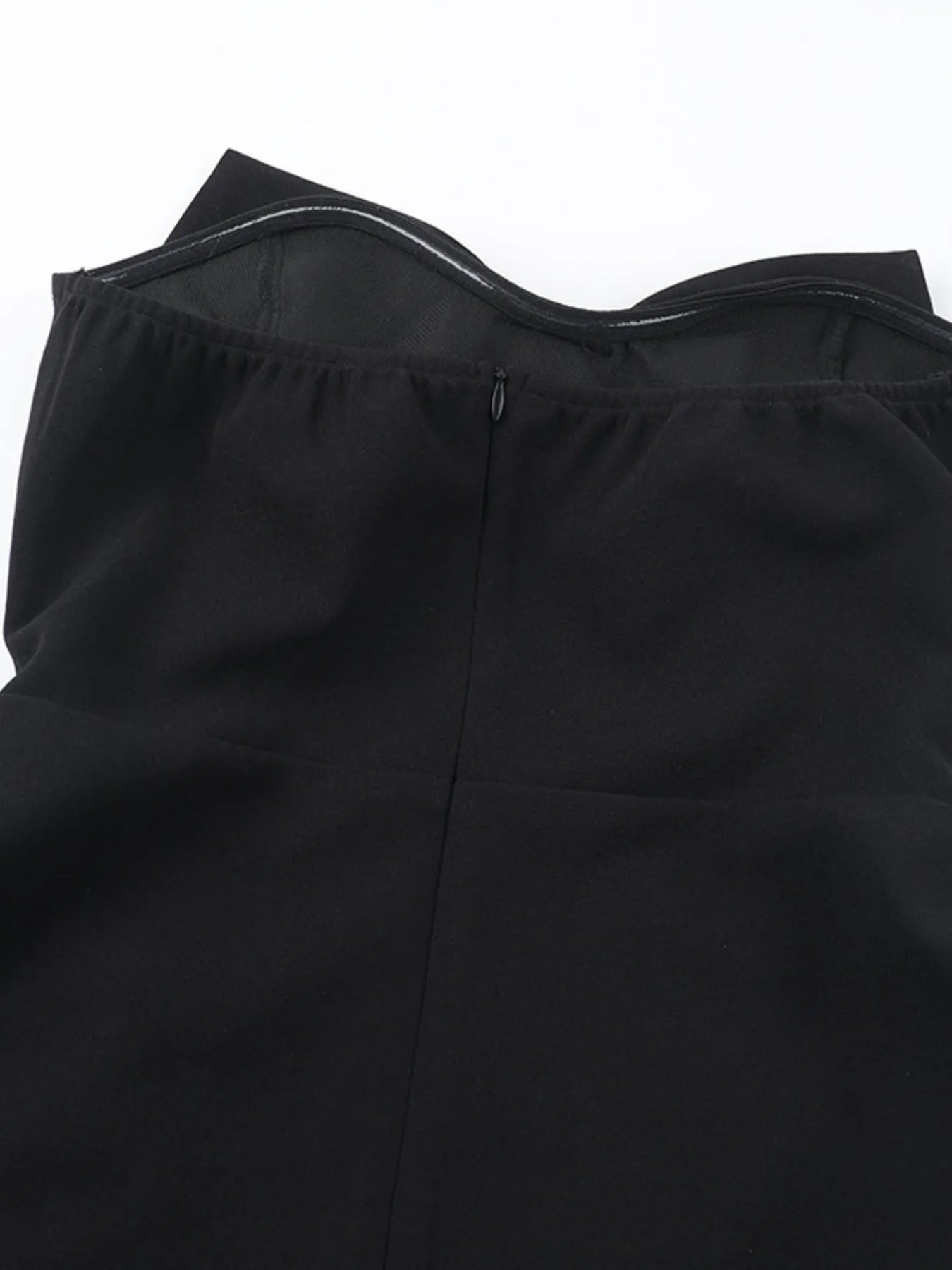 Close-up of a black strapless top with a zipper on a white background