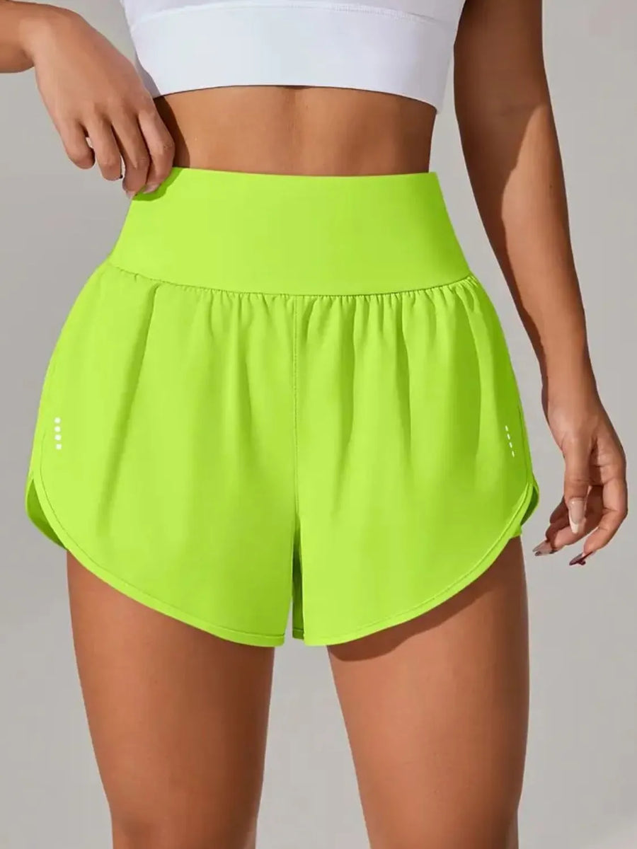Person wearing bright green athletic shorts and a white top on a plain background