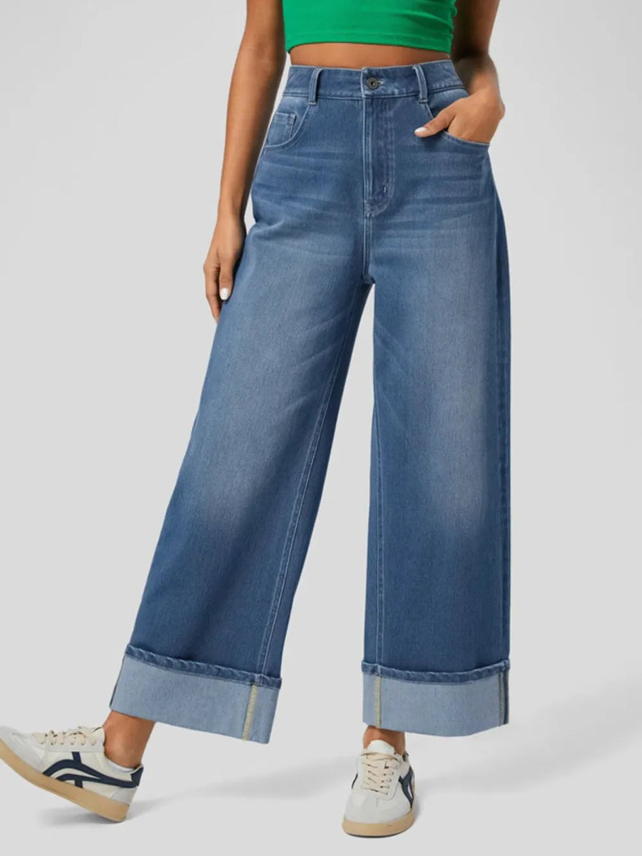 Person wearing blue wide-leg jeans on a plain background