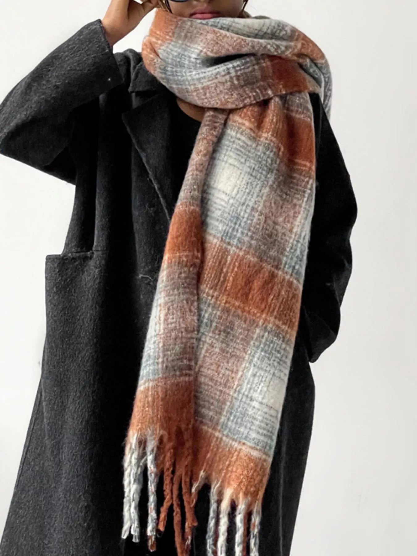 Person wearing a plaid scarf with orange and gray colors on a white background