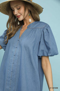 Woman wearing a light blue dress with puff sleeves against a solid background