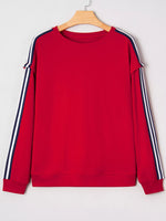 Red sweatshirt with white and navy stripes on sleeves hanging on a wooden hanger against a white background
