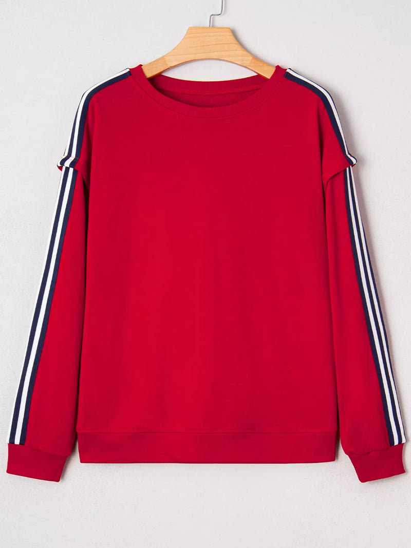 Red sweatshirt with white and navy stripes on sleeves hanging on a wooden hanger against a white background