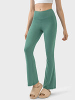 Green flared pants worn by a person on a white background
