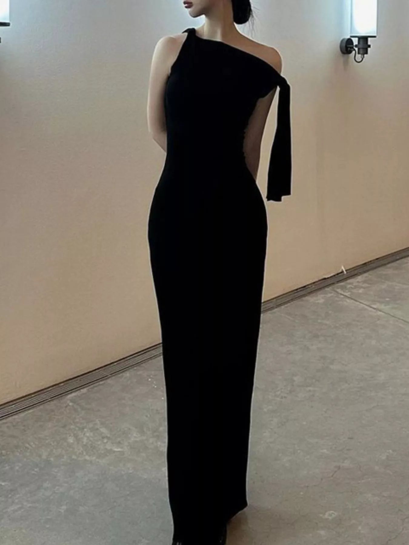 Black one-shoulder dress with cut-out design on a plain background