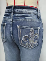 Blue jeans with a decorative fleur-de-lis pocket on a plain background