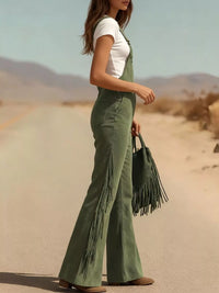 Person wearing green fringed overalls and white top in a desert setting