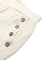 Close-up of a cream-colored fabric with wooden buttons on a white background
