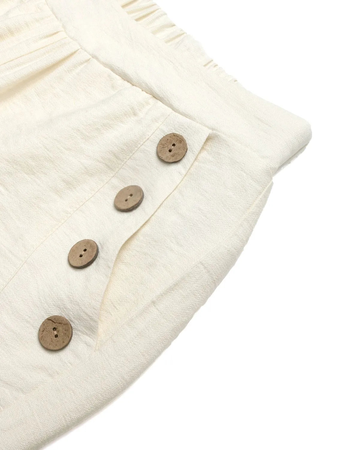 Close-up of a cream-colored fabric with wooden buttons on a white background