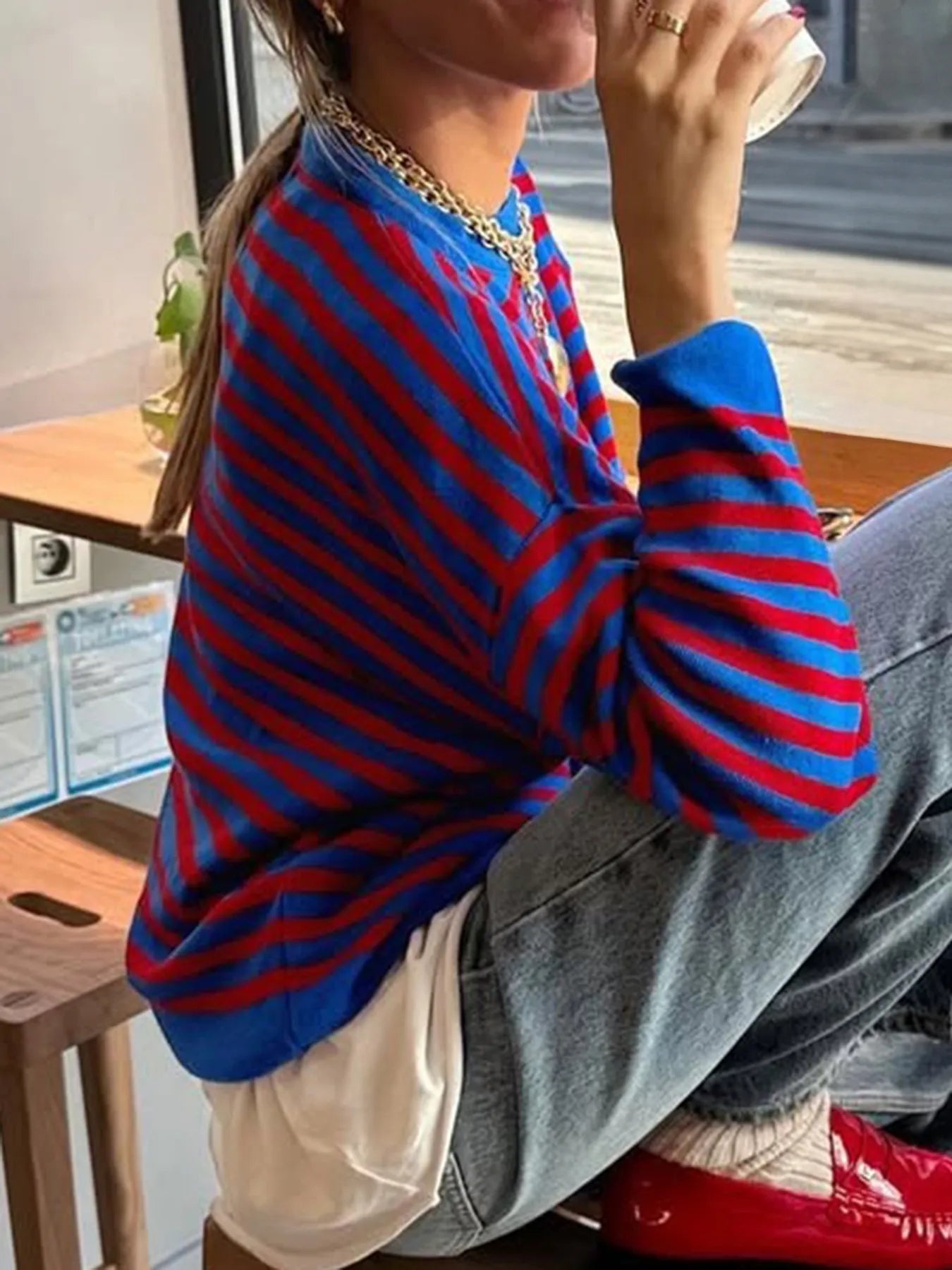 Person wearing a blue and red striped sweater sitting indoors.