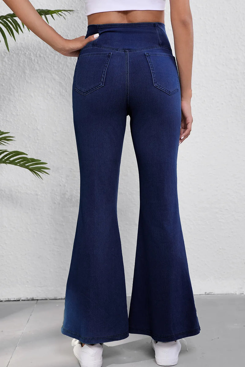 Navy blue flared jeans worn by a person on a white background