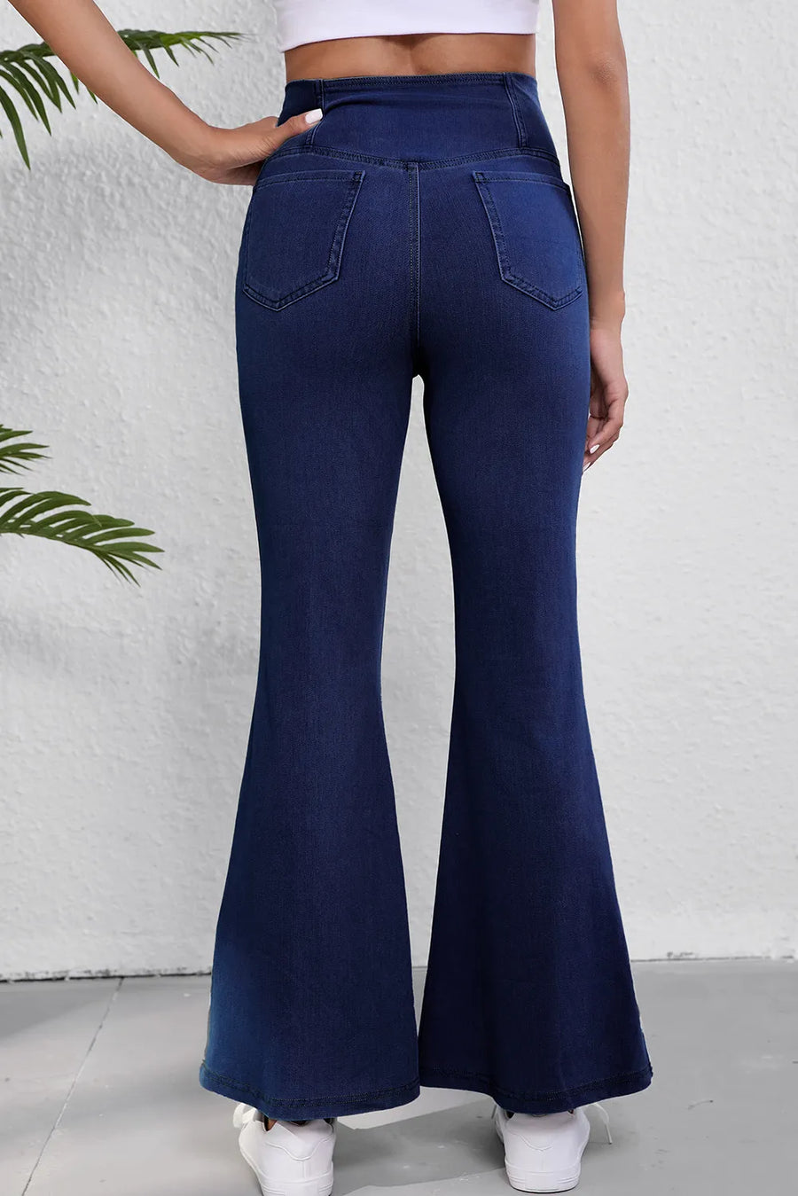Navy blue flared jeans worn by a person on a white background