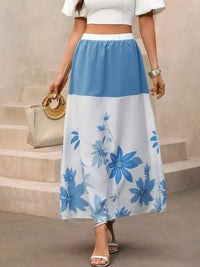 Person wearing a white top and blue floral skirt standing on steps.
