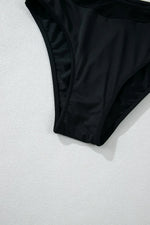 Black bikini bottom on a textured white surface