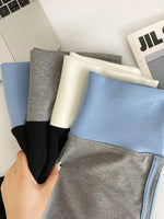 Person holding fabric swatches in front of a laptop and newspaper.