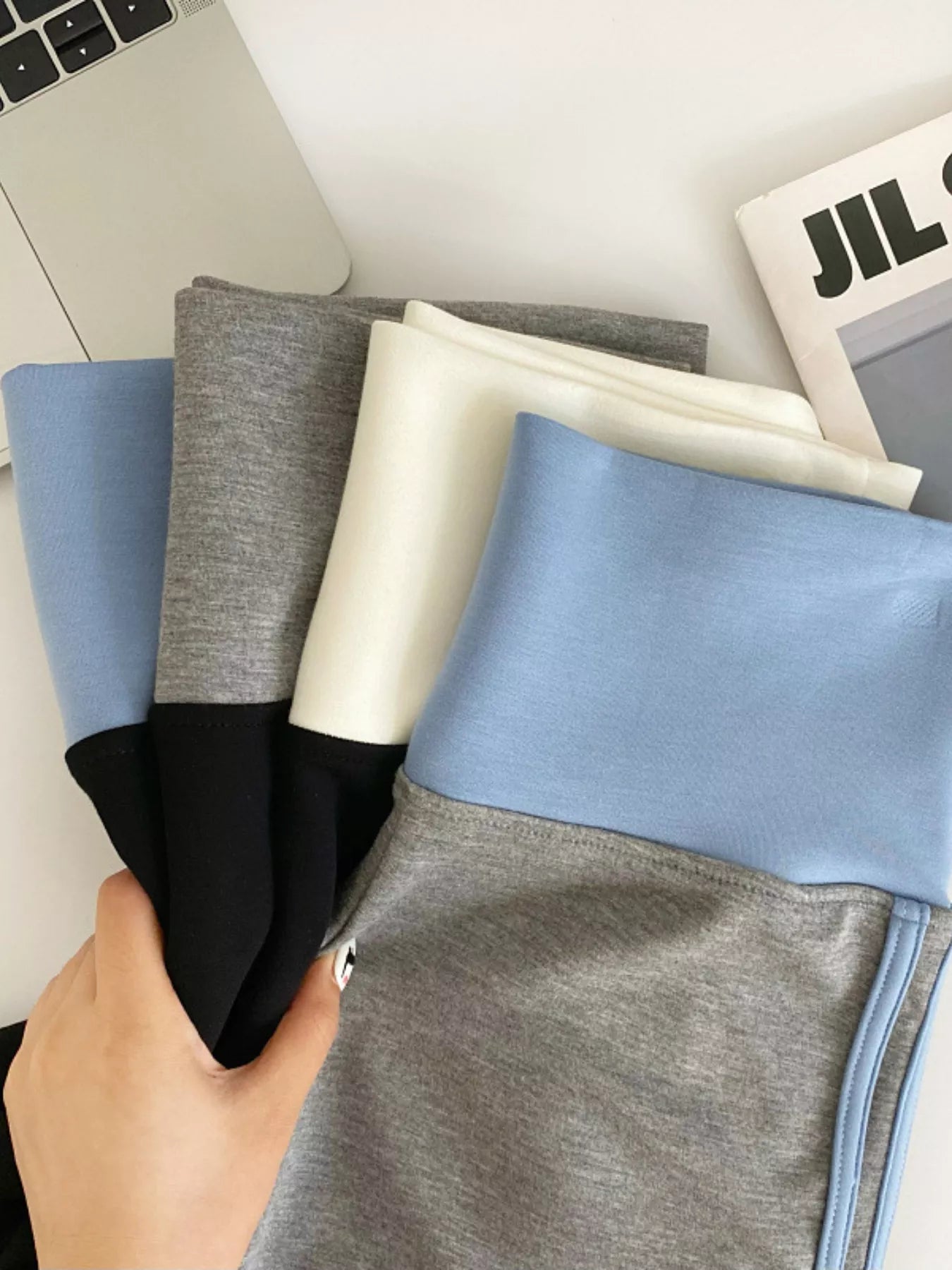 Person holding fabric swatches in front of a laptop and newspaper.