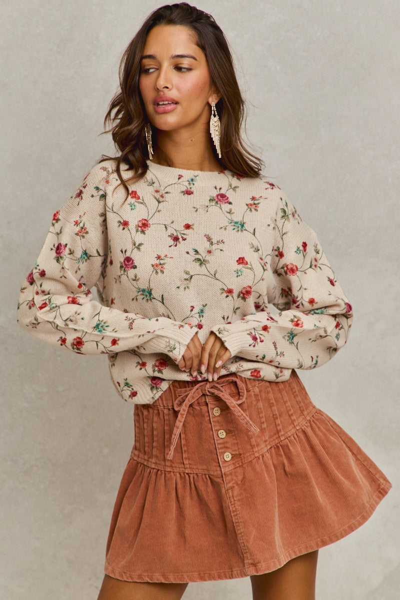 Woman wearing a floral blouse and brown skirt against a neutral background