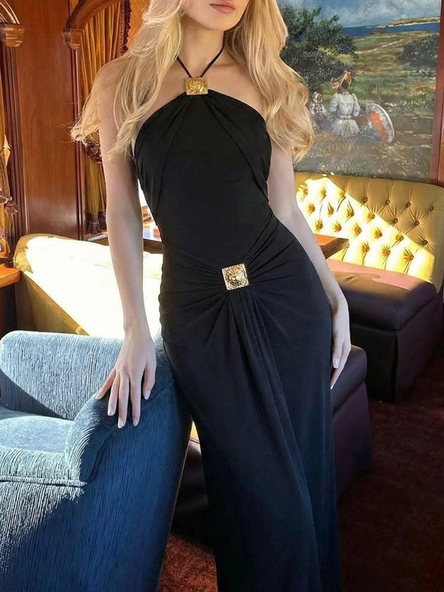 Woman in a black dress with a gold belt in an elegant room.