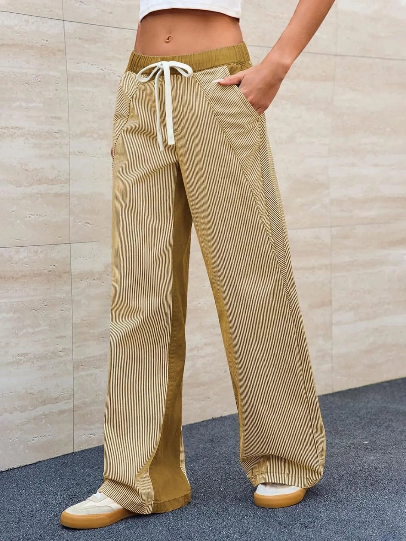 Person wearing beige corduroy pants with a drawstring against a beige wall.