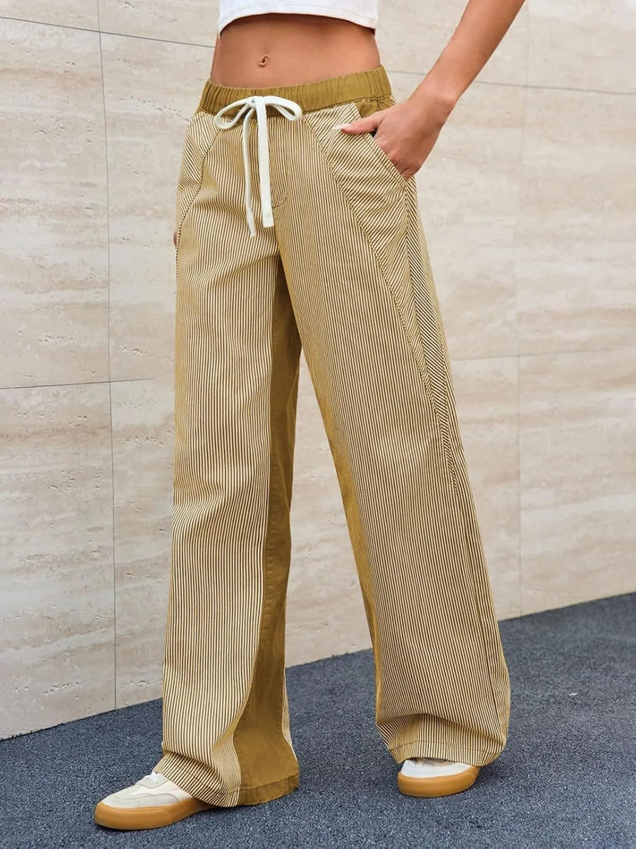 Person wearing beige corduroy pants with a drawstring against a beige wall.