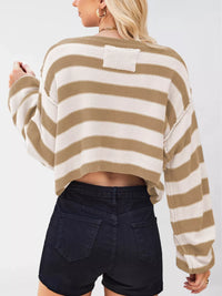 Person wearing a striped sweater and dark shorts on a plain background