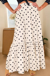 Person wearing a white polka dot skirt with a neutral background